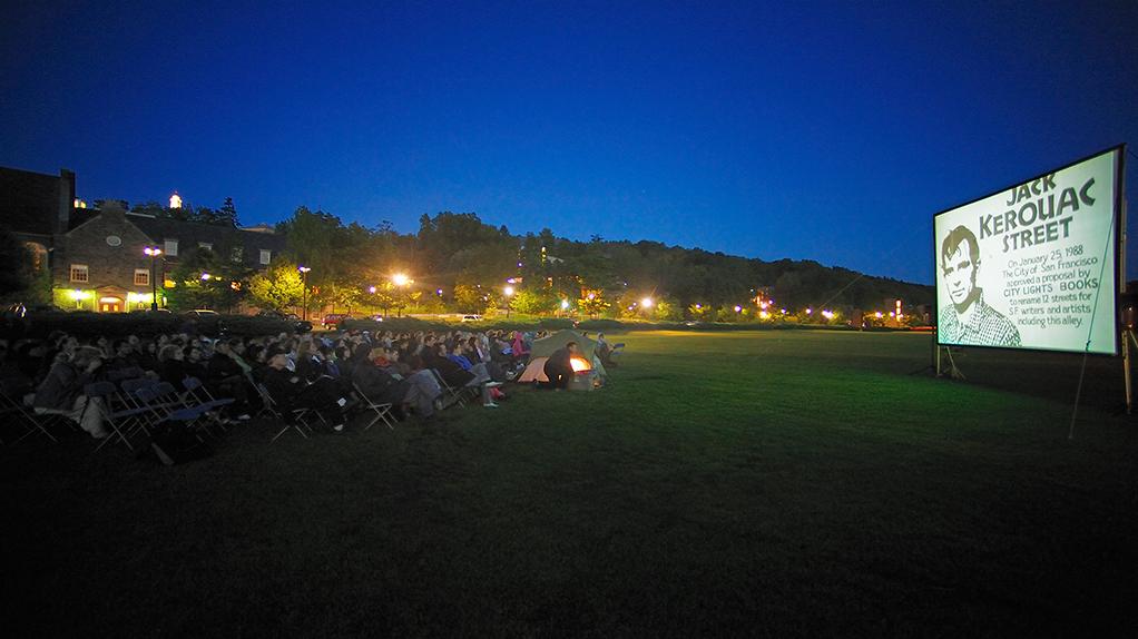 Students watching outdoor movie in the evening on campus.